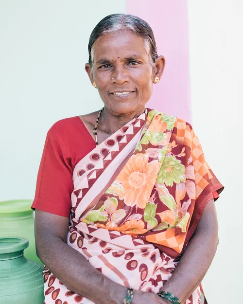 Woman smiling sitting in front of vessels of water.